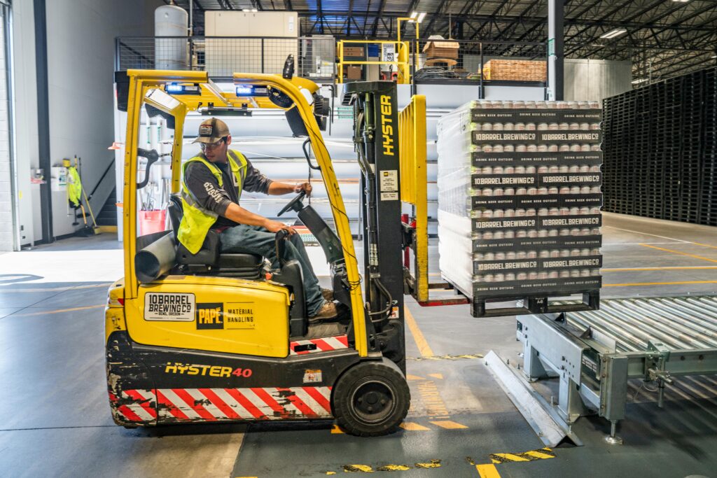 A worker using a yellow forklift.